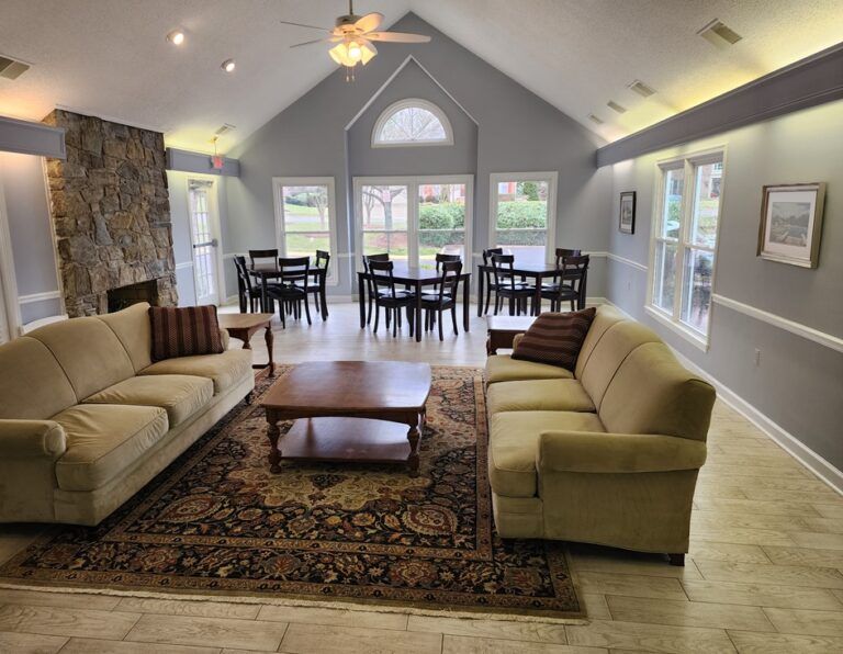 Clubhouse common room with a stone fireplace, sofas and dining tables